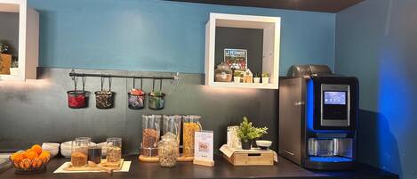 A kitchen with a coffee machine, jars of spices, and a hanging rack with kitchen utensils.