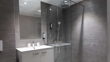 A modern bathroom with a glass-enclosed shower, a white vanity with a mirror, and a toilet.