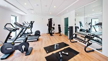 Een moderne sportschool met cardioapparatuur, krachtstations en spiegels.
