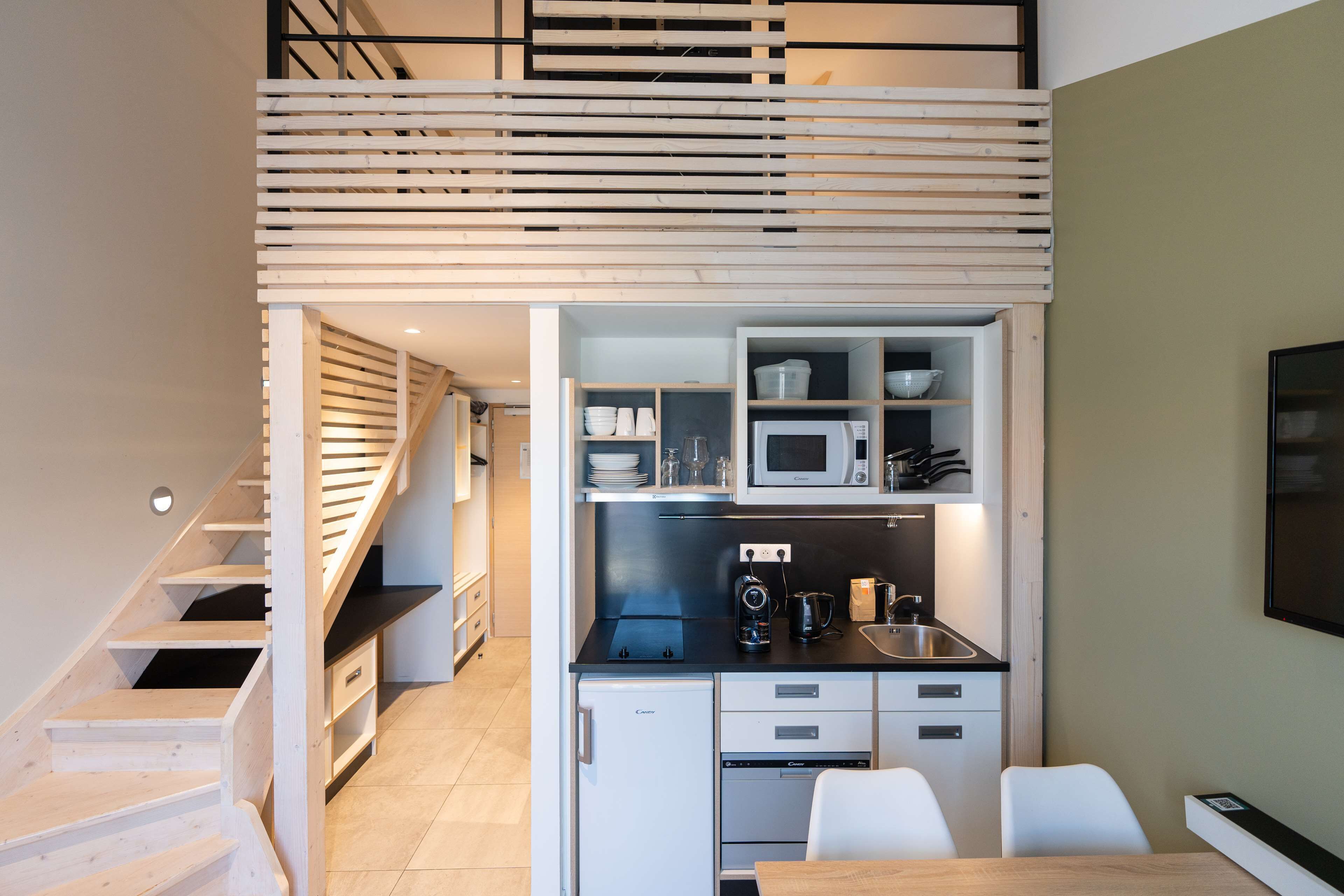 A compact kitchen with a microwave, sink, and storage cabinets. A small dining table with chairs is visible.
