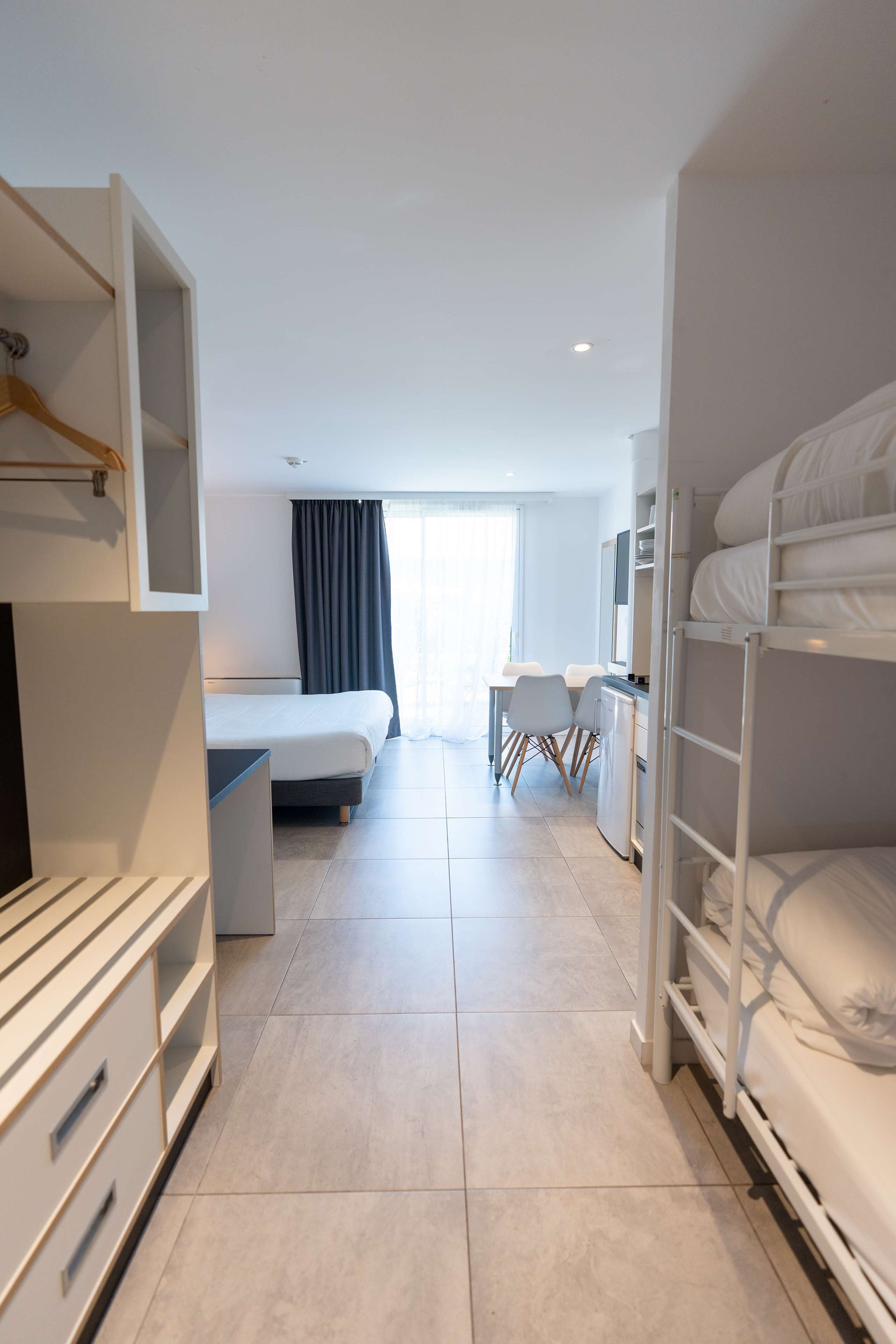 Habitación de hotel con literas, un escritorio con silla, un armario y una cama con escritorio.