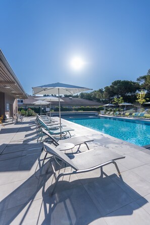 A pool area with lounge chairs and umbrellas, a clear sky, and a mountain in the background. - Appart'hôtel Kyriad Résidence Cabriès - Plan de Campagne (Cabries)
