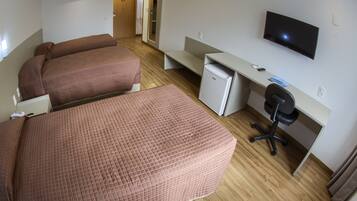 Habitación de hotel con dos camas, un escritorio, un refrigerador pequeño, un televisor y una silla.
