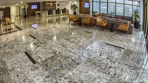 A hotel lobby with a reception desk, seating area, and large windows. - Marante Executive Hotel (Recife)