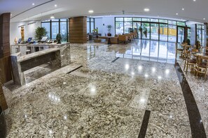 A spacious lobby with a marble floor, seating area, and large windows offering a view of the outside. - Marante Executive Hotel (Recife)