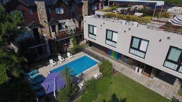 Um edifício residencial moderno com piscina, área de estar externa e jardim bem cuidado.