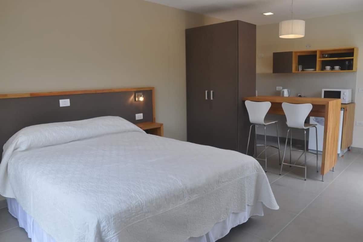 A hotel room with a large bed, a desk with two chairs, a microwave, and a wardrobe.