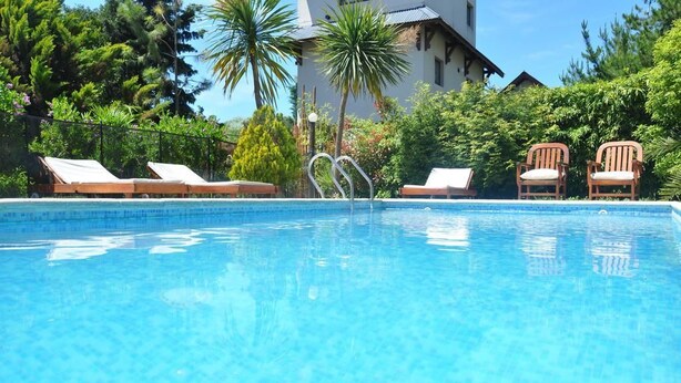 A clear blue pool with lounge chairs and a house in the background. - Solar Pampa Apart Hotel (Mar de Las Pampas)