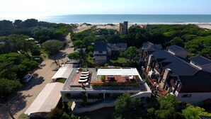 An aerial view of a coastal residential area with houses, a beach, and a clear sky. - Solar Pampa Apart Hotel (Mar de Las Pampas)
