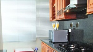 A kitchen with wooden cabinets, a gas stove, and a toaster. - Apartamentos Morros 427 Cartagena (Cartagena)