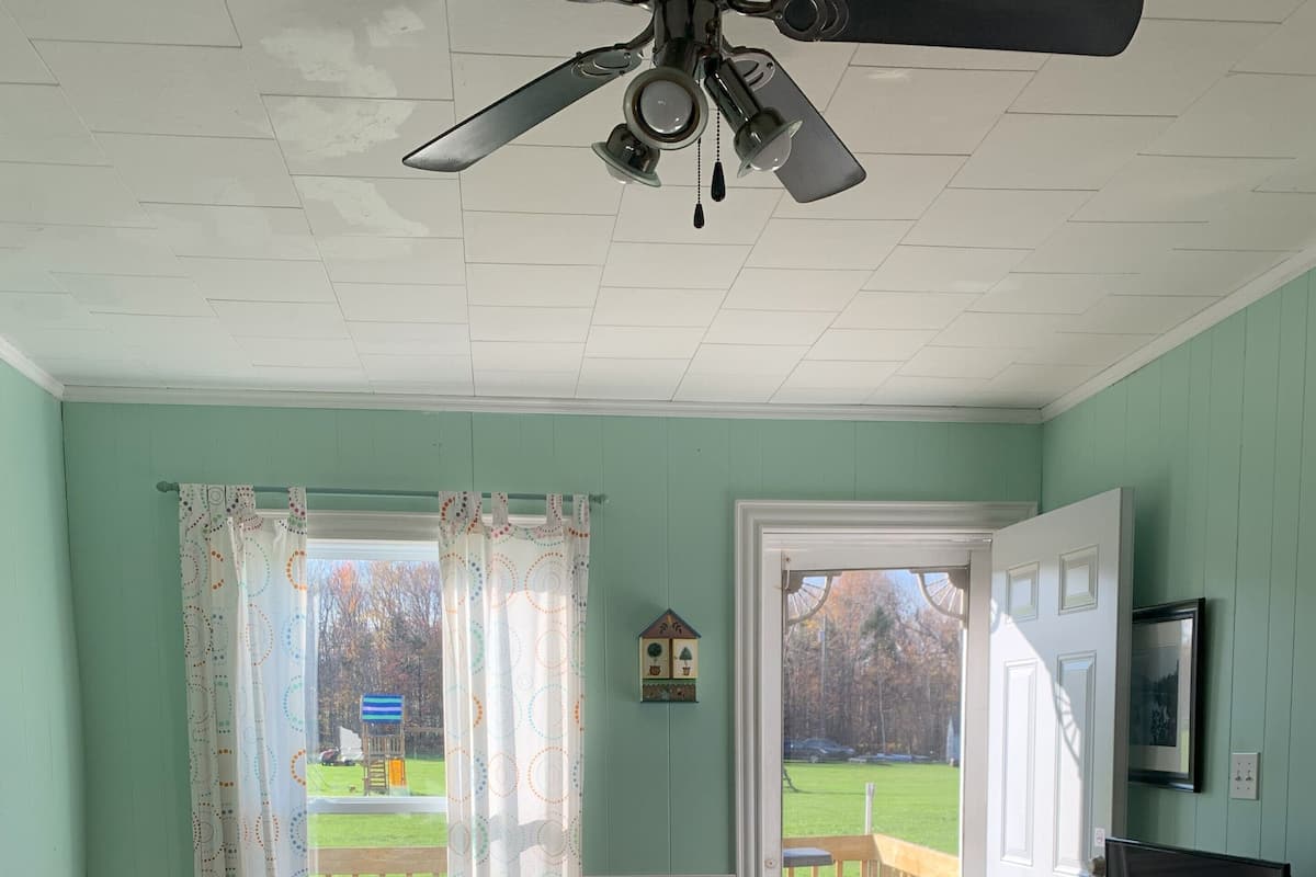 A cozy living room with a dining area, a television, and a ceiling fan.