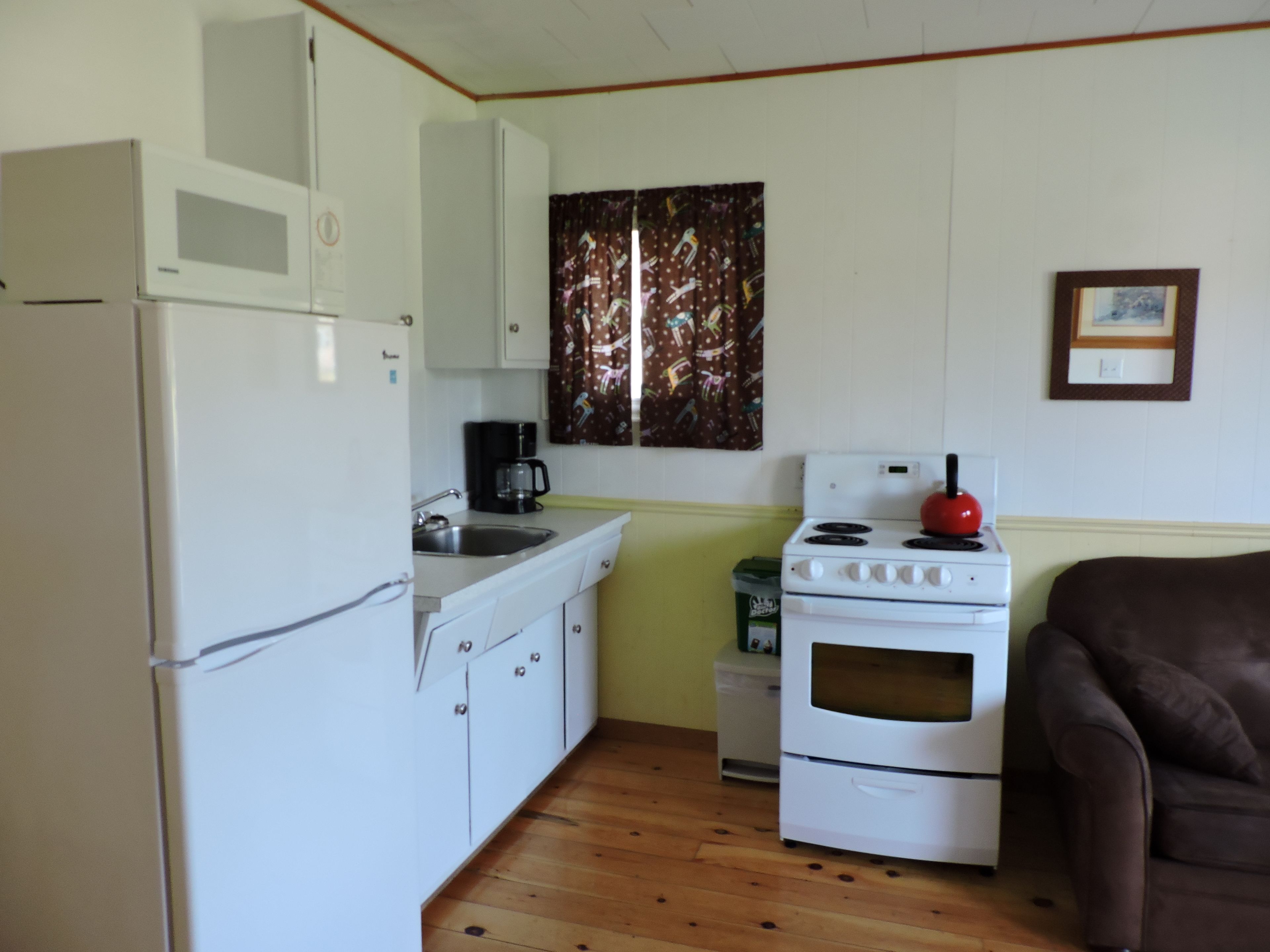 A compact kitchen with white appliances, a sink, and a stove.