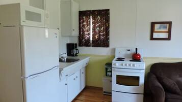 A compact kitchen with white appliances, a sink, and a stove.