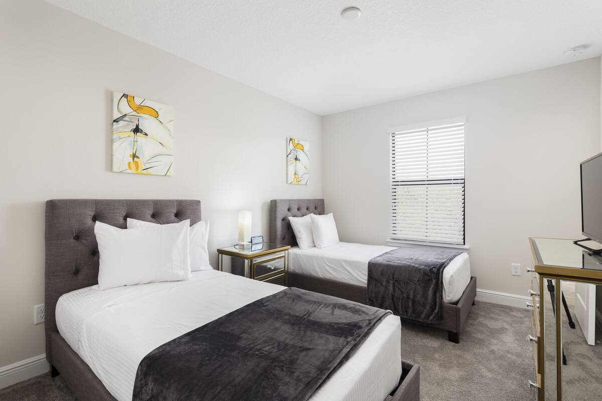 A hotel room with two beds, a desk, and artwork on the walls.