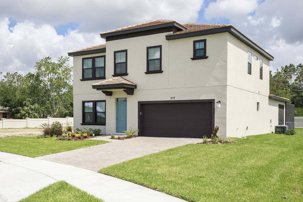 A two-story modern house with a garage, numbered 215, and a well-maintained lawn.