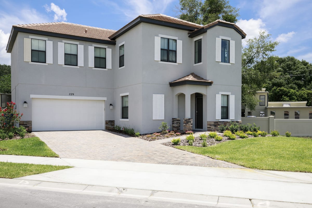 A two-story house with a garage, a front entrance with a door, and a driveway leading to the garage.