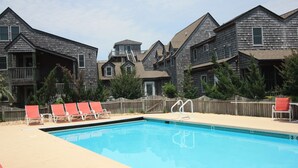 A swimming pool with lounge chairs, wooden deck, and a wooden fence.