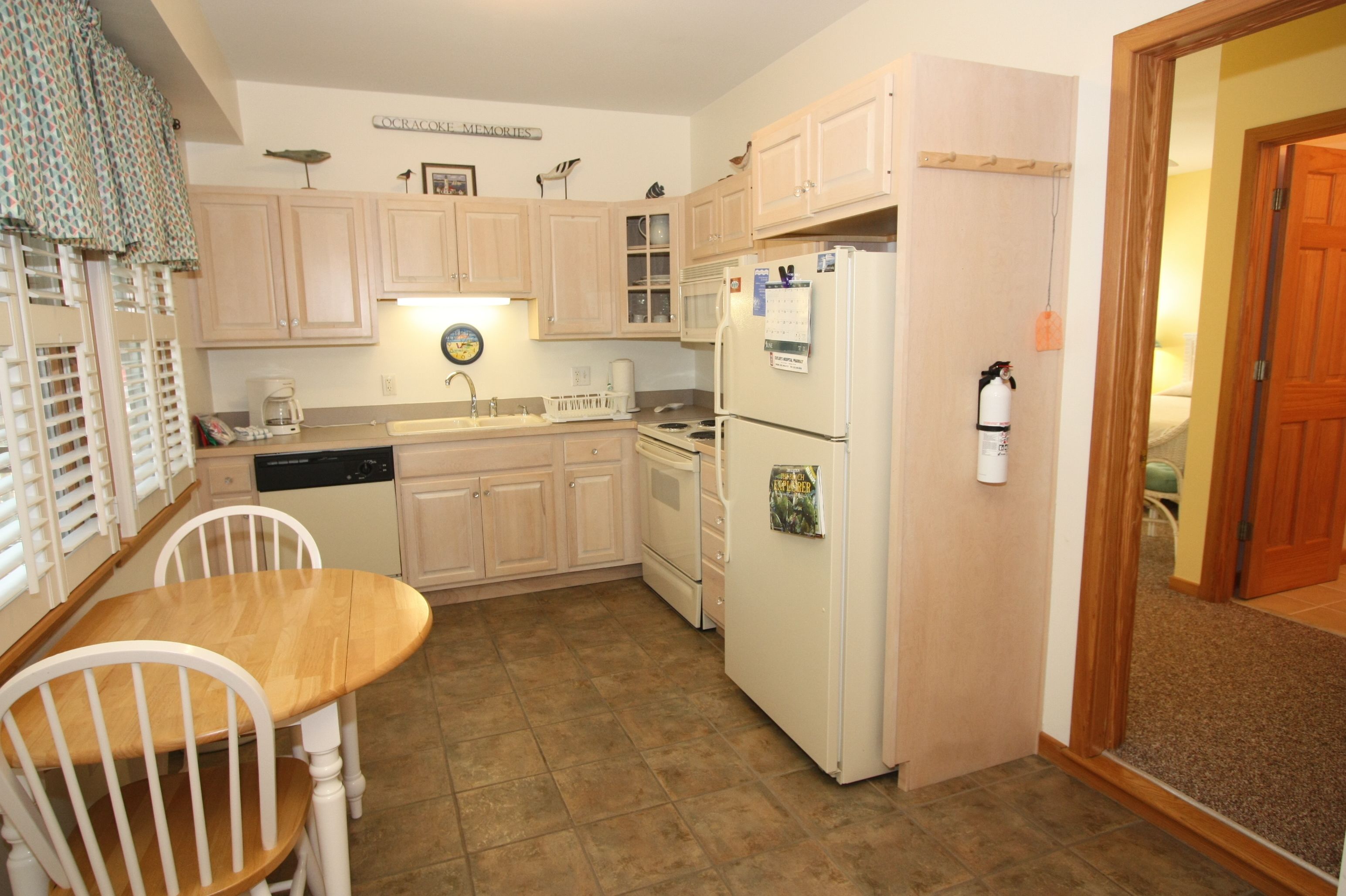 Una cocina compacta con muebles de madera, un refrigerador, un fregadero y una mesa de comedor con sillas.