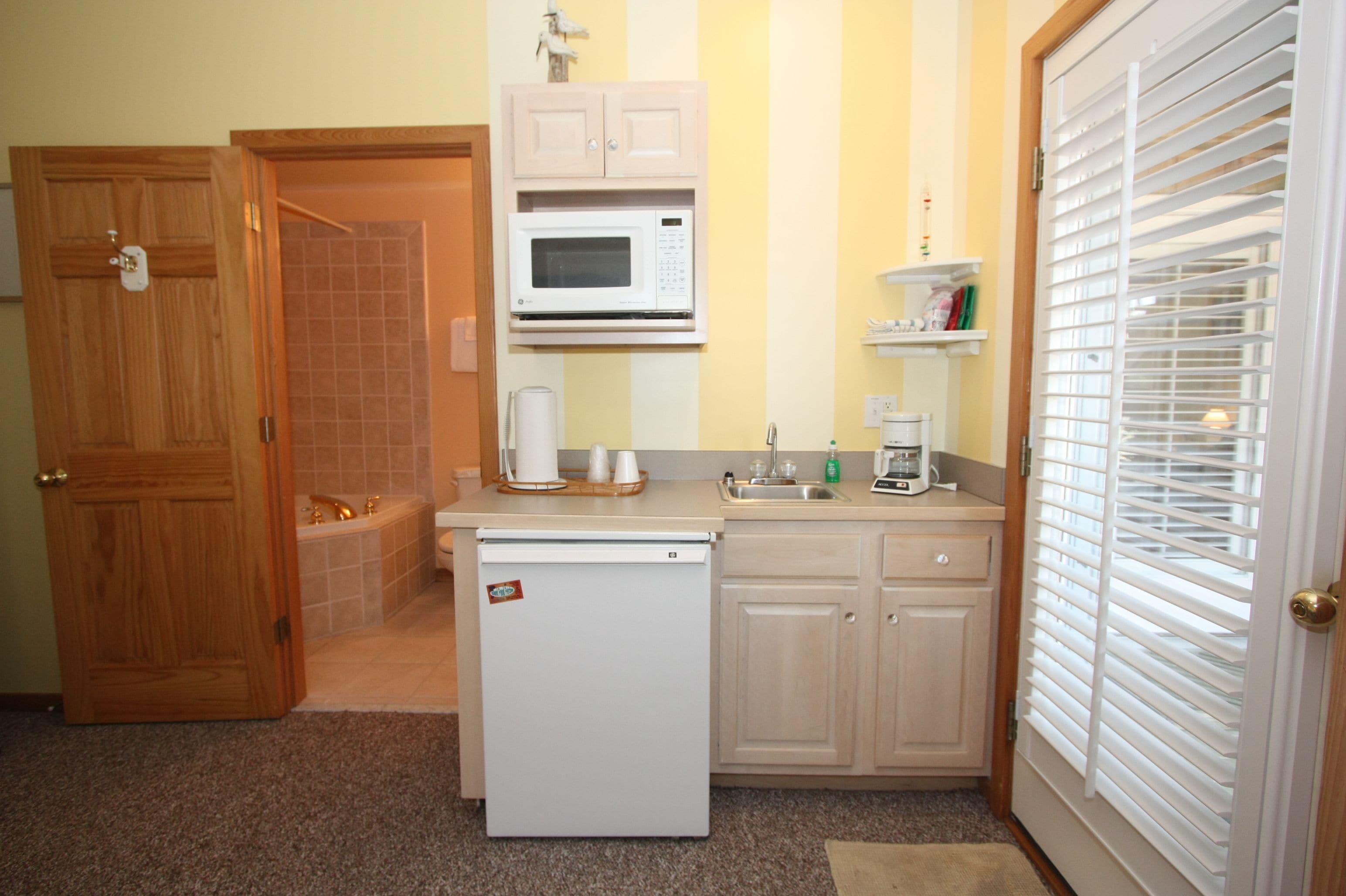 Una cocina compacta equipada con refrigerador, microondas y lavamanos.