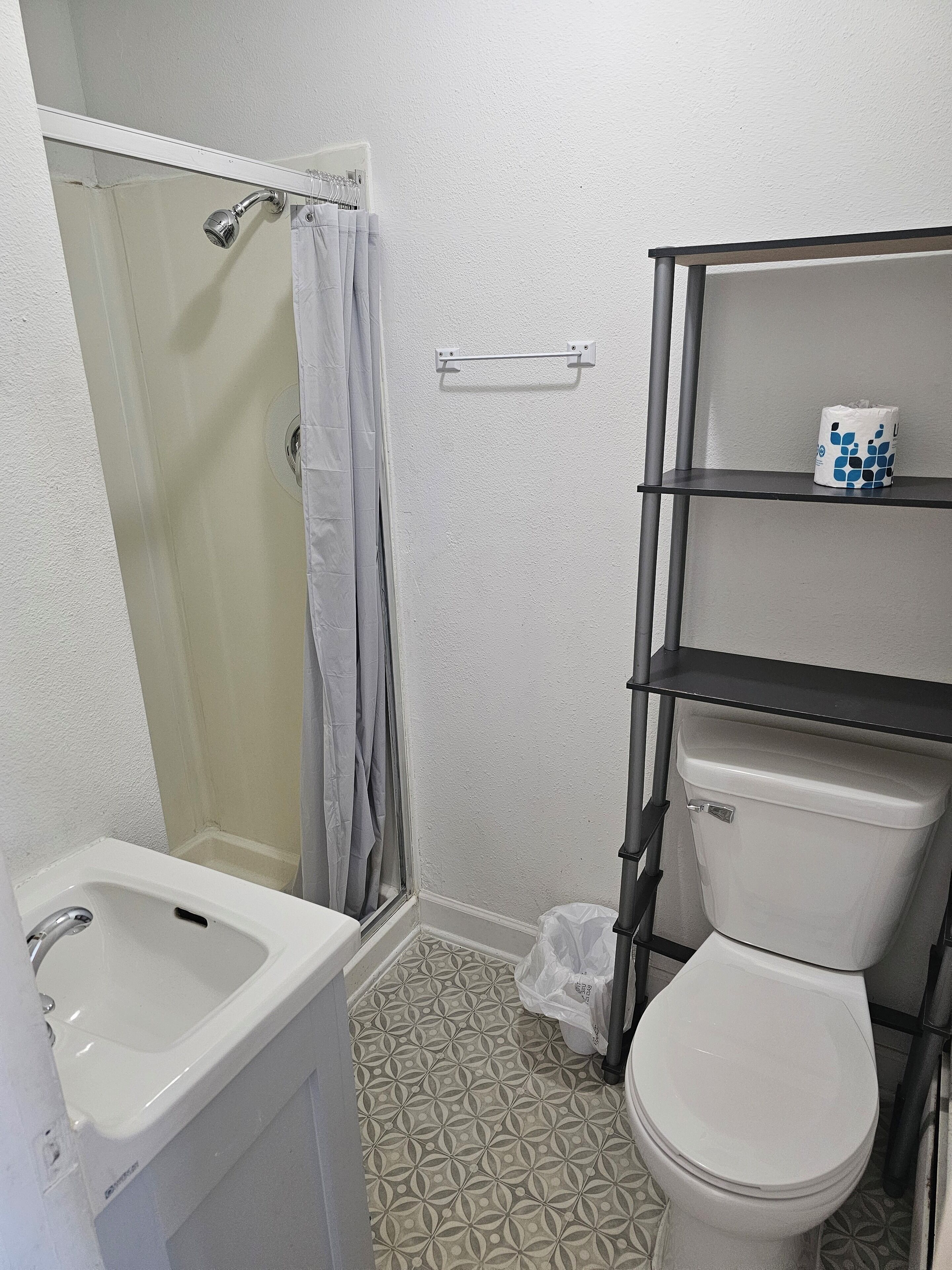 A bathroom with a shower, toilet, and sink.