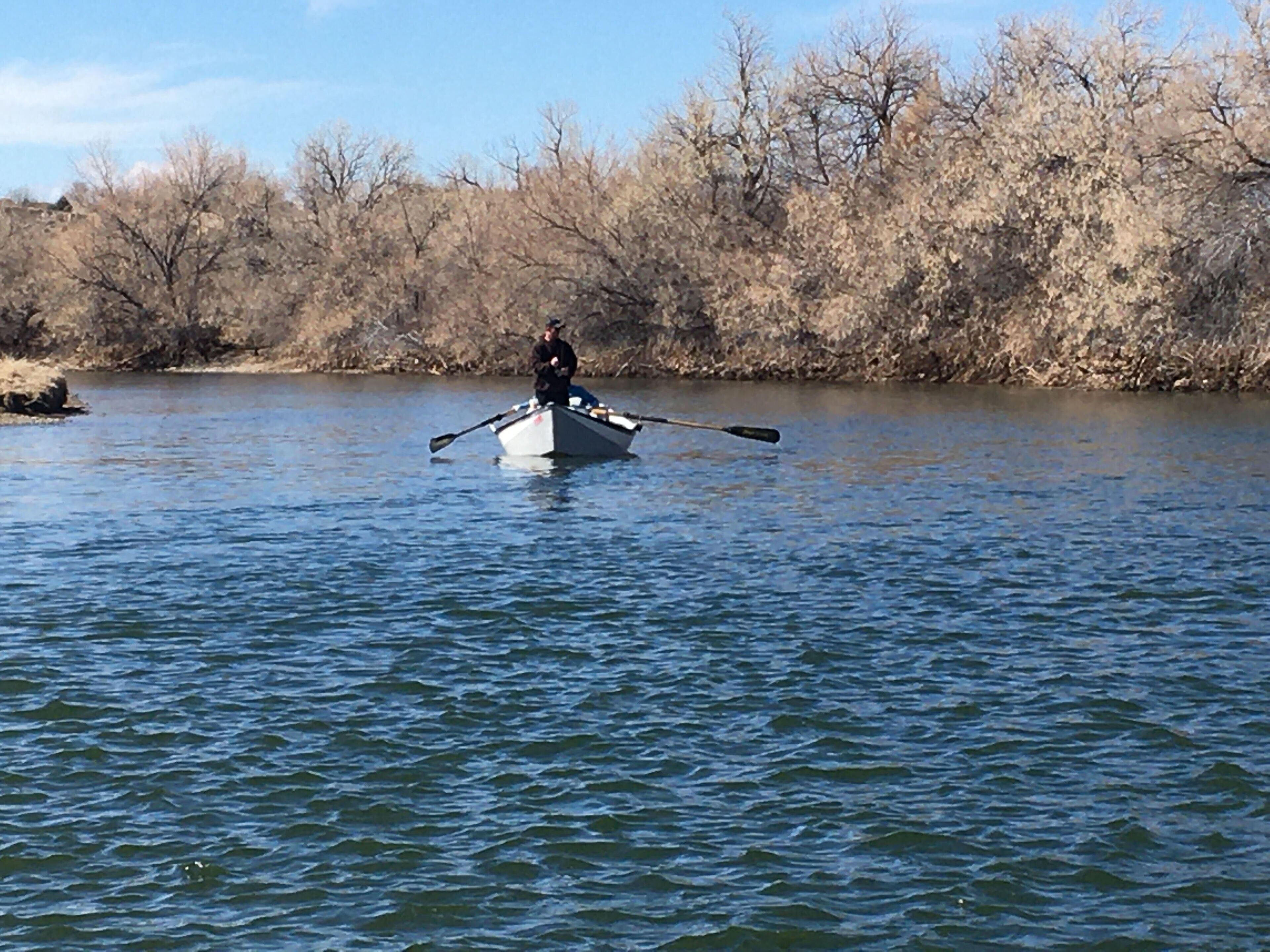 Eine Person fährt in einem Boot auf einem ruhigen Fluss.