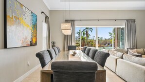 A modern living room with a large sofa, a dining table with chairs, and a large abstract painting on the wall. - Liberty Square: Private Pool, Games Room, Golf View, Near Disney (Kissimmee)