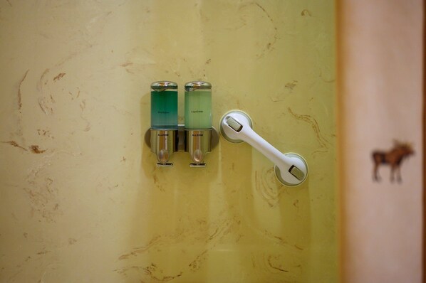 A bathroom with two soap dispensers labeled "Allzone" and a white hand dryer.
