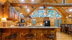 Una cocina rústica con armarios de madera, encimera de granito y taburetes de bar.