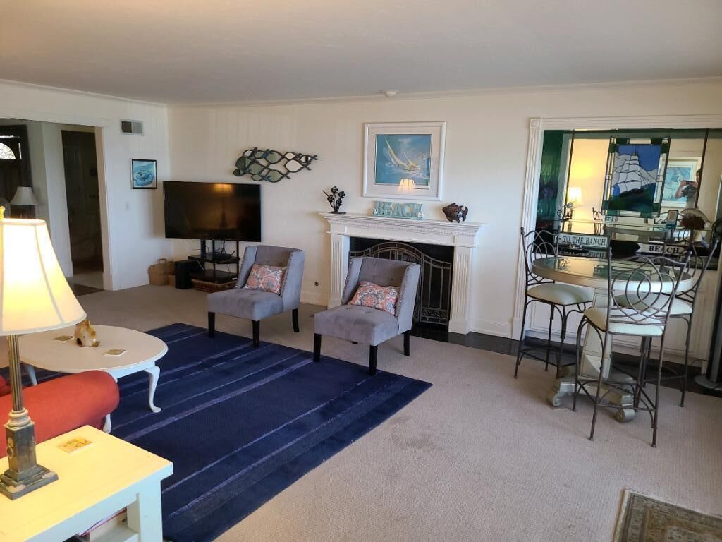 Un salon doté d’une cheminée, d’un téléviseur et d’un coin repas avec des chaises en métal.