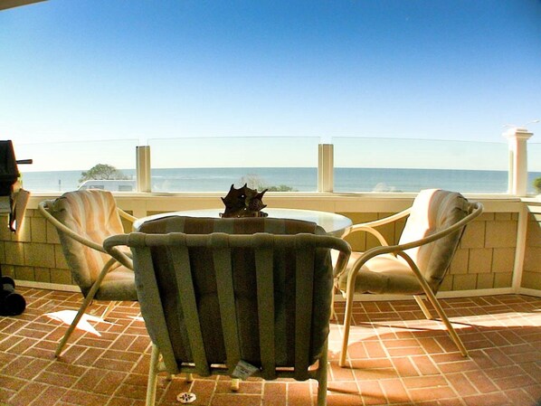 A patio with two chairs and a table, overlooking a body of water.