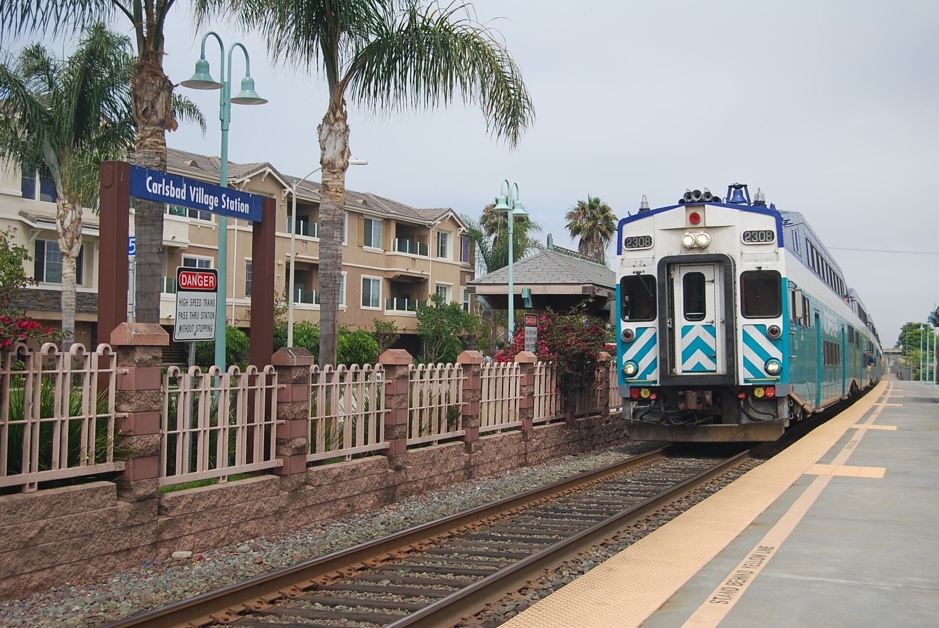 A train at a station with a sign for Carlsbad Village Station.