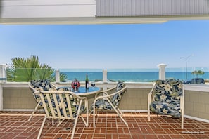 A patio with a table and chairs, a bottle of wine, and a view of the ocean.