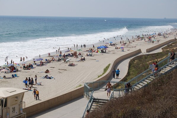 A beach with people sunbathing and walking along the shore.