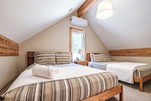 A bedroom with two beds, wooden headboards, a window, and an air conditioning unit. - Heated Pool in Winter, Sleeps 18, 10 Min to Sunday River, Mountain Views (Bethel)