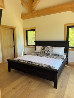 Una camera da letto con un letto in legno, due finestre e una porta.