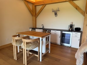 Una cocina con vigas de madera, encimera blanca, un fregadero y una cafetera.