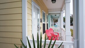 A yellow building with a white porch and red chairs. - Beautiful Beach Style Cottage, One Block from Beach.  (Myrtle Beach)