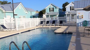 A swimming pool with a white fence, lounge chairs, and a lifeguard stand. - Beautiful Beach Style Cottage, One Block from Beach.  (Myrtle Beach)