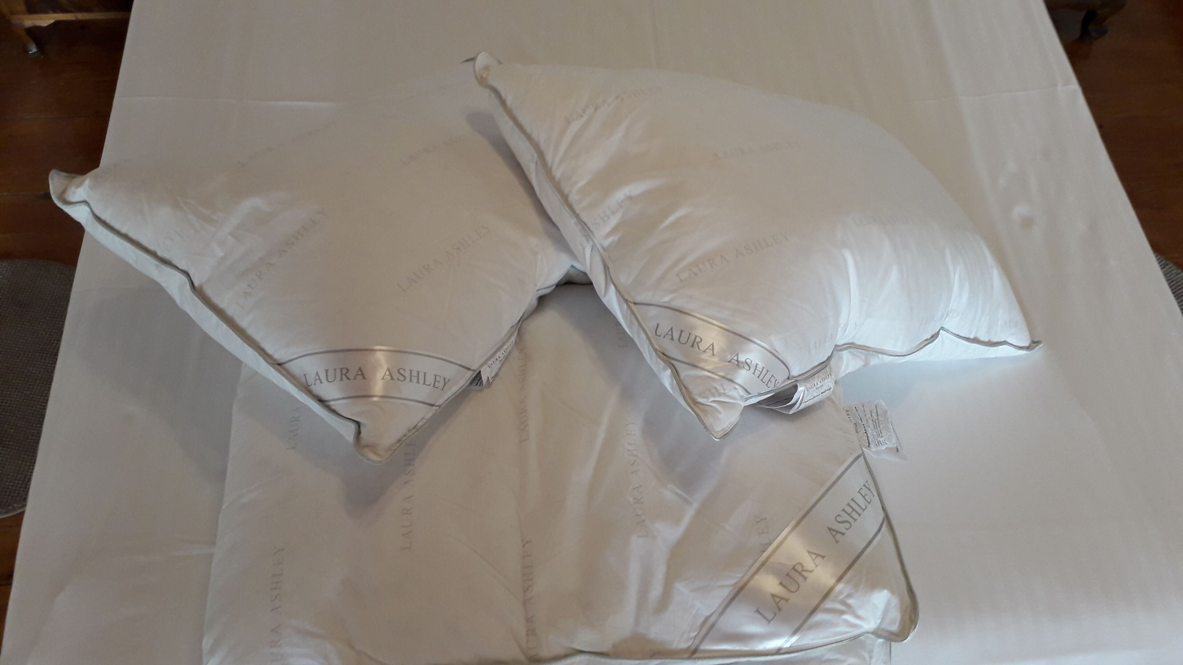 Deux coussins sur lesquels est inscrit le texte « LAURA ASHLEY », posés sur une surface blanche.