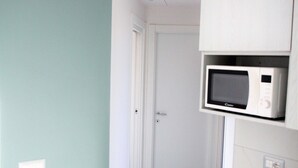 A kitchen with a microwave, white cabinets, and teal walls.