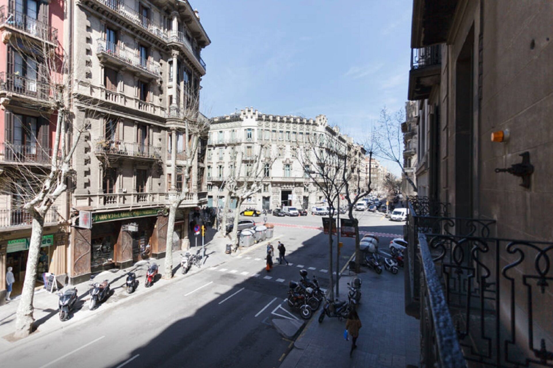 Vista callejera con motocicletas estacionadas, cielo despejado y edificios de varios pisos con balcones.