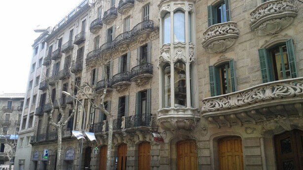 Eine Reihe historischer Gebäude mit verzierten Balkonen und grünen Fensterläden.