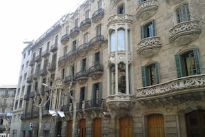 Una hilera de edificios históricos con balcones ornamentales y contraventanas verdes.