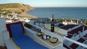 A balcony with a view of the sea, a bottle of wine, and a table with food and glasses. - Casa Cian Luxury 8th floor apartment with stunning 270° Sea View,140m from beach (Praia da Luz)
