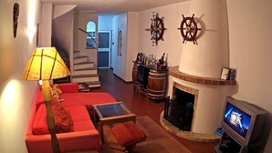 A living room with a red sofa, a TV, a fireplace, and a staircase leading to another room. - Casa Cian Luxury 8th floor apartment with stunning 270° Sea View,140m from beach (Praia da Luz)