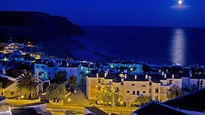 A coastal town at night with buildings illuminated, a beach, and a visible moon. - Casa Cian Luxury 8th floor apartment with stunning 270° Sea View,140m from beach (Praia da Luz)
