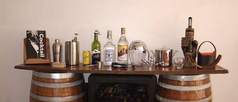 Zona de bar con una rueda de timón de madera, varias botellas y un shaker de cócteles.