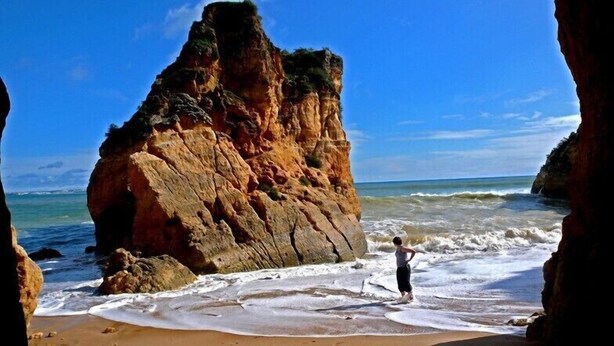 A beach with a large rock formation and waves crashing onto the shore. - Casa Cian Luxury 8th floor apartment with stunning 270° Sea View,140m from beach (Praia da Luz)
