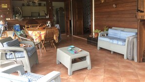 A spacious living area with wicker furniture, a dining table, and a kitchen in the background. - Villa with panoramic view on the islets of Robert and natural swimming pool  (LE ROBERT)