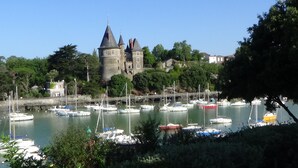 A historic castle with a tower, surrounded by a marina with various boats.